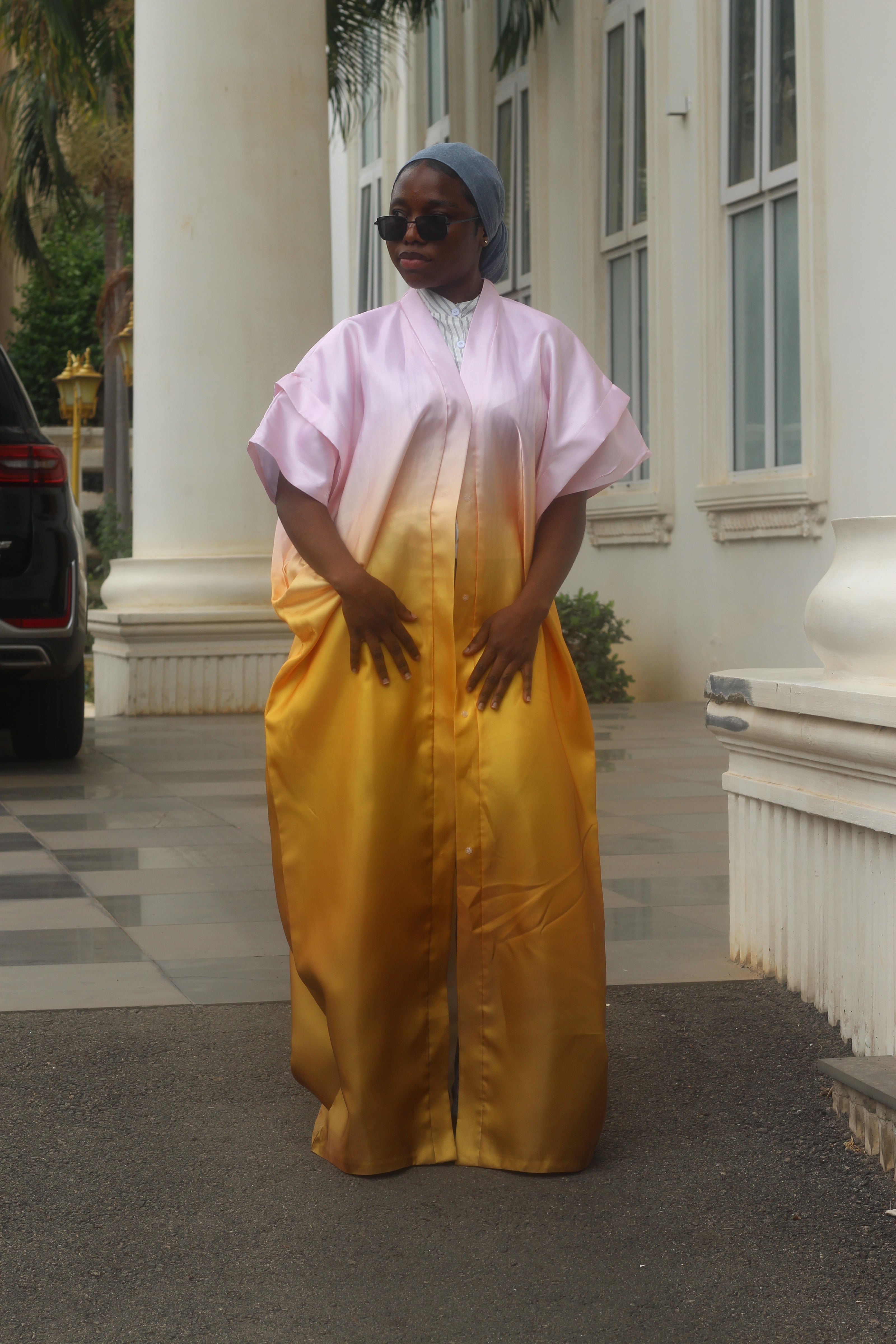 


Woman wearing a yellow and pink traditional Owambe House outfit standing in front of a building.